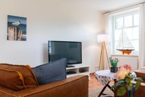 ein Wohnzimmer mit einem Sofa und einem Flachbild-TV in der Unterkunft Ferienhaus Canvas Canvas Carolinensiel FeWo "Spiekeroog" in Carolinensiel