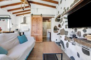 een woonkamer met een bank en een tv aan een stenen muur bij Ca Lajares in Lajares
