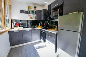 - une cuisine avec des armoires en noir et blanc et un réfrigérateur dans l'établissement Lynx, à Pontarlier