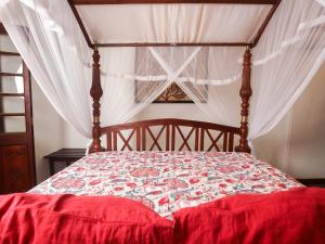 um quarto com uma cama de dossel e um edredão vermelho em Andiramada Walawwa em Rambukkana