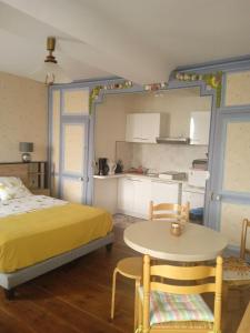 1 dormitorio con cama, mesa y cocina en Chambres d'hôtes les Clématites en Cotentin, en Saint-Floxel