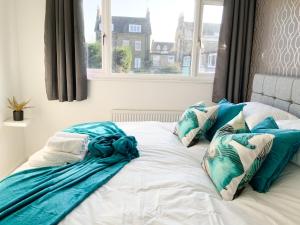 - un lit avec des oreillers bleus et blancs et une fenêtre dans l'établissement De Montfort House, à Londres