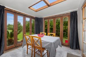 a dining room with a table and chairs and windows at 39 North - Tutukaka Holiday Home in Tutukaka