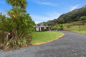 39 North - Tutukaka Holiday Home في توتوكاكا: منزل على تلة مع ممر