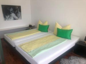 2 bedden in een kamer met groene en gele kussens bij Lochau Sonnenuntergang genießen in Lochau