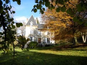 duży biały dom z drzewami na dziedzińcu w obiekcie LA MAISON D'EULALIE w mieście La Chapelle-du-Bard