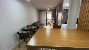 a room with a wooden table and a living room at Flat beira lago no centro de BSB in Brasilia