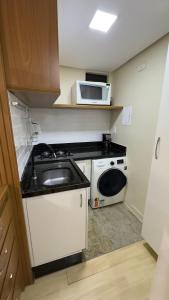 a small kitchen with a sink and a microwave at Flat beira lago no centro de BSB in Brasilia