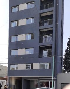 un edificio alto con un coche aparcado delante de él en Dptos amoblados NQN - Excelente ubicacion- ZONA CENTRO en Neuquén