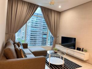 ein Wohnzimmer mit Couch und großem Fenster in der Unterkunft Soho Suites KLCC By Grand Suites KL in Kuala Lumpur