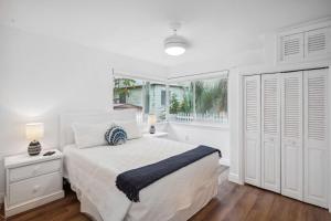 een witte slaapkamer met een bed en een raam bij Beach Livin 1 - 1 Bedroom Downstairs in St Pete Beach