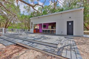 a large deck with a white building with a purple door at The Driftwoods - Orange Tiny House in Driftwood