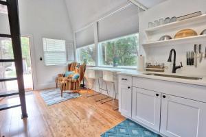 a kitchen with white cabinets and a large window at The Driftwoods - Orange Tiny House in Driftwood