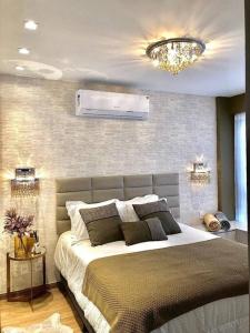 Un dormitorio con una cama grande y una lámpara de araña. en Gramado Centro ao lado das compras e Rua Coberta Vita, en Gramado