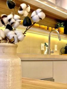 Un jarrón con flores sobre una mesa en una cocina. en Gramado Centro ao lado das compras e Rua Coberta Vita, en Gramado