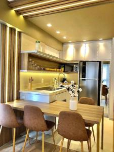 cocina con mesa de madera con sillas y nevera en Gramado Centro ao lado das compras e Rua Coberta Vita, en Gramado