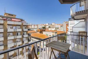 a balcony with a wooden table and a view of a city at Urban Elegance Apartment in Almada