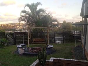 a garden with a bench and a palm tree at East-Coast Guesthouse: Serene, Private, Secure in Durban