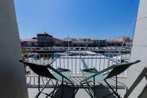 two chairs sitting on a balcony with a marina at La maison du Port Apt ROMA in Marseillan