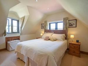 a bedroom with a large white bed with two windows at Little Lock Cottage in Horsham