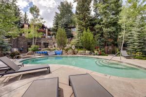 a swimming pool with chaise lounge chairs in a backyard at Ski-InandOut Oversized Aspen Studio with Pool and Hot Tub in Snowmass Village