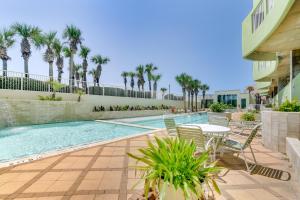 a swimming pool with a table and chairs and palm trees at Oceanfront Galveston Condo in Amazing Location! in Galveston