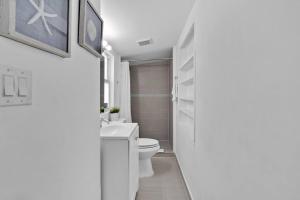 a white bathroom with a toilet and a sink at Lovely 1 Bedroom Walking Distance To Ocean - Suite 1 in Hollywood +13 photos
