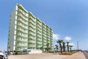 a tall building with palm trees in front of it at Oceanfront Galveston Condo in Amazing Location! in Galveston