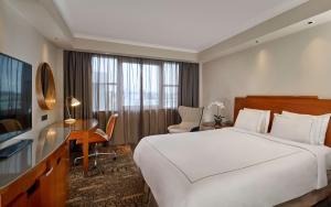 Una habitación de hotel con una cama, un escritorio y un televisor. en Park Plaza Victoria London, en Londres