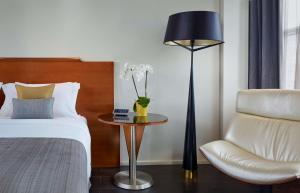 ein Schlafzimmer mit einem Bett, einem Stuhl und einer Lampe in der Unterkunft Park Plaza Victoria London in London