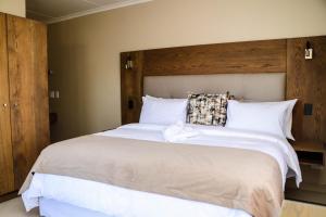 um quarto com uma grande cama branca e uma cabeceira em madeira em Windhoek Gardens Boutique Hotel em Windhoek