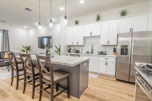 a kitchen with white cabinets and a kitchen island with chairs at New! Houston Luxury Haven near Dwtn, Med CTR in Houston