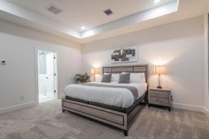 a white bedroom with a bed and a night stand with two lamps at New! Houston Luxury Haven near Dwtn, Med CTR in Houston