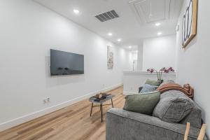 a living room with a couch and a tv on a wall at New! Houston Luxury Haven near Dwtn, Med CTR in Houston