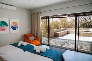 a bedroom with two beds and an orange chair at Elements Bush Villa 295 in Mabula