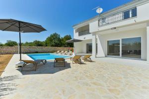 uma villa com uma piscina com cadeiras e um guarda-sol em Villa Natura with pool, Zadar county em Stankovci