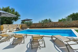 uma piscina com cadeiras e um guarda-sol em Villa Natura with pool, Zadar county em Stankovci
