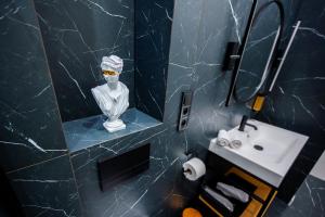 a bathroom with a sink and a statue in the mirror at Apartamenty Poniatowskiego in Przemyśl