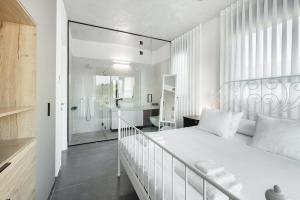 a white bedroom with a white bed and a bathroom at Top Tlv in Tel Aviv