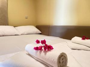 Una cama blanca con toallas y flores. en Spacious Villa With a Pool, en Nea Peramos