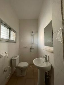 a white bathroom with a toilet and a sink at Résidence Le TOUNKARANKE ACI 2000 in Bamako