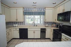 a kitchen with white cabinets and a sink and a window at The Earnest at Ships Watch in Duck
