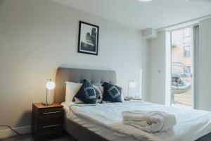 a bedroom with a bed with white sheets and a window at Stunning 2-Bed Apartment in Birmingham City Center in Birmingham