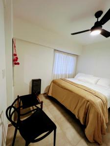 a bedroom with a bed and a chair and a ceiling fan at Departamento Catedral in Santa Rosa