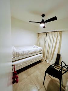 a bedroom with a bed and a chair and a ceiling fan at Departamento Catedral in Santa Rosa