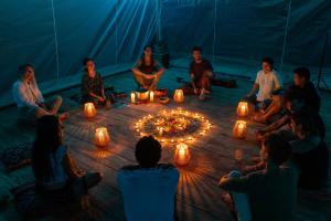 un grupo de personas sentadas alrededor de un círculo con velas en AWAKEN Amazonian Healing Resort ALL INCLUSIVE, en Iquitos