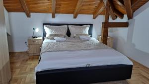 a bedroom with a large bed with white sheets and wooden ceilings at Apartman Bubic 