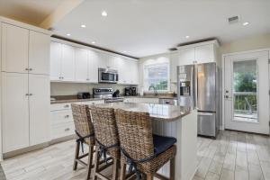 a kitchen with white cabinets and bar stools at The Powell at Ships Watch in Duck