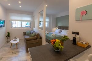 Mandevilia Suites في أثينا: غرفة معيشة مع سرير وطاولة مع وعاء من الفاكهة