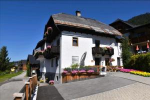 a white building with a balcony and flowers at Haus Binder in Weissensee